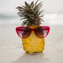 ananas-dimezzato-e-un-occhiale-da-sole-conservati-sulla-sabbia_1252-505
